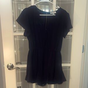 Black polyester shorts romper with flutter detail on the bottom hem